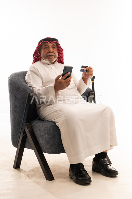 رجل سعودي مسن يستخدم الهاتف والبطاقة الائتمانية