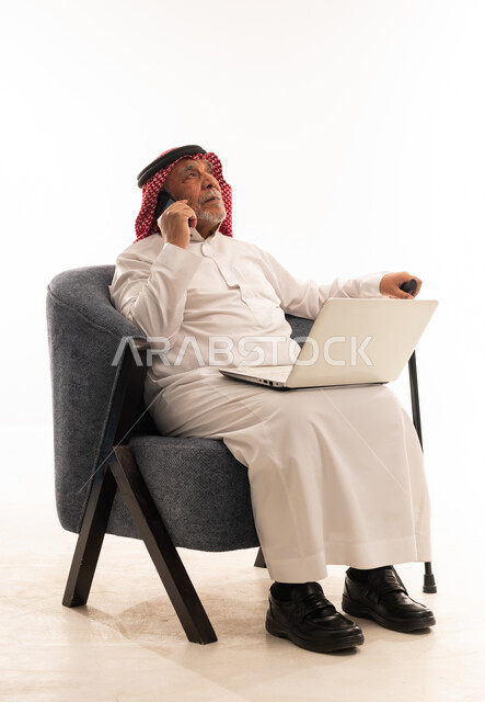 رجل سعودي مسن يستخدم الجوال واللابتوب خلفية بيضاء