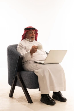 رجل سعودي مسن يستخدم المحمول ويشرب القهوة