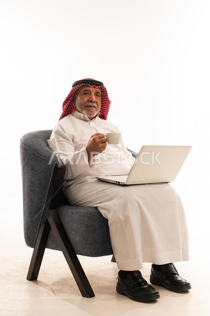 رجل سعودي مسن مع لابتوب وقهوة بخلفية بيضاء