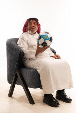 رجل سعودي مسن بالزي التقليدي يمسك كرة قدم