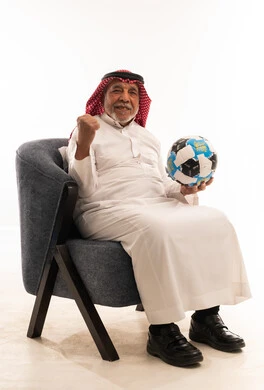 رجل سعودي مسن يحتفل ممسكاً بكرة القدم في استوديو