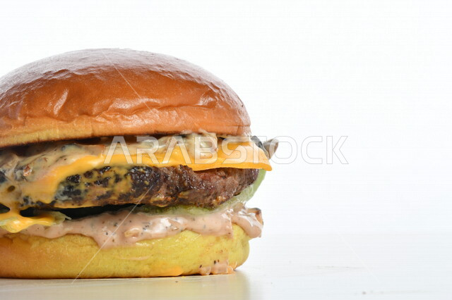 Close-up of a delicious hamburger sandwich stuffed with meat, cheese, lettuce and different flavors, delicious burger meal pictured on a white background, fast food, Arabic restaurants, delicious food