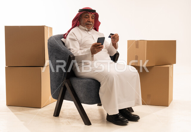 رجل سعودي مسن يتسوق إلكترونياً مع صناديق شحن