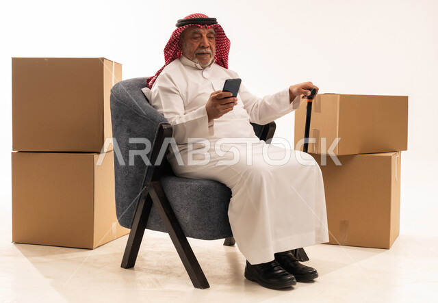 Elderly Saudi Man with Smartphone and Moving Boxes