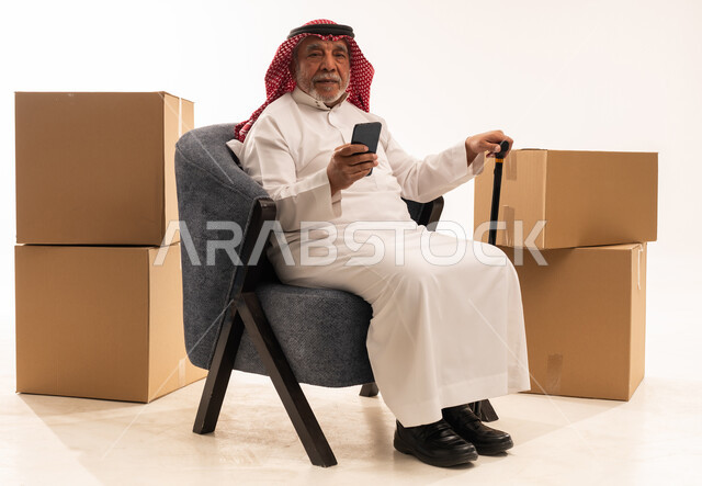 Elderly Saudi Man with Smartphone and Moving Boxes