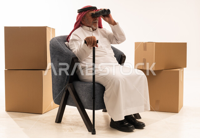 رجل سعودي مسن مع منظار وصناديق كرتونية للانتقال