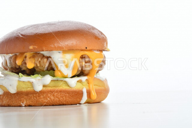 Close-up of a delicious hamburger sandwich stuffed with meat, cheese, lettuce and different flavors, delicious burger meal pictured on a white background, fast food, Arabic restaurants, delicious food