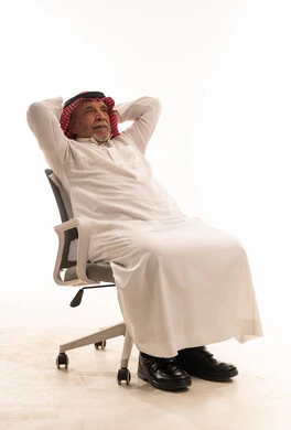 رجل سعودي مسن يسترخي على كرسي مكتب خلفية بيضاء