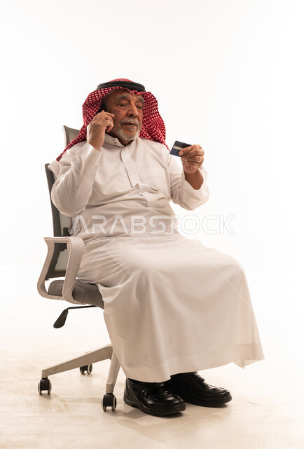 رجل سعودي مسن يستخدم بطاقة الائتمان والهاتف الذكي