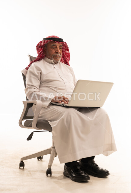رجل سعودي مسن يستخدم المحمول على كرسي مكتب