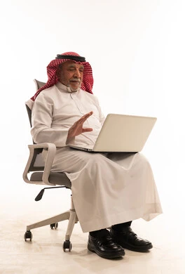 رجل سعودي مسن يستخدم اللابتوب بخلفية بيضاء