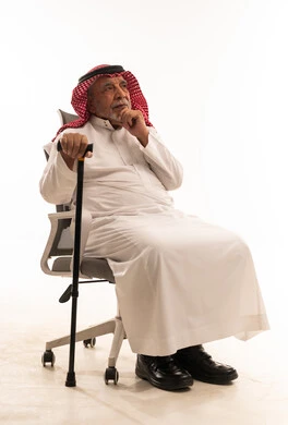 Elderly Saudi Man in Traditional Thobe Sitting with Cane