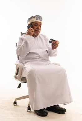 Omani Senior Man Using Credit Card on Smartphone