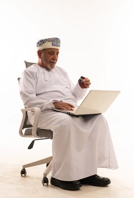 رجل عُماني مسن يستخدم الحاسوب والبطاقة البنكية