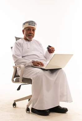 رجل عماني مسن يستخدم المحمول وبطاقة الائتمان