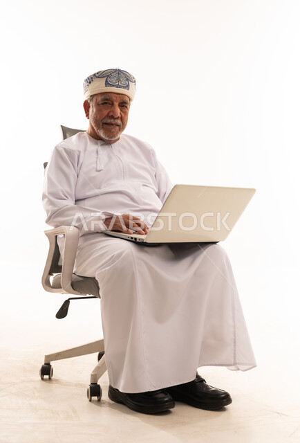 رجل عماني مسن يستخدم المحمول على خلفية بيضاء