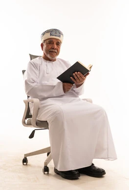 رجل عماني مسن بالزي التقليدي يقرأ كتاباً