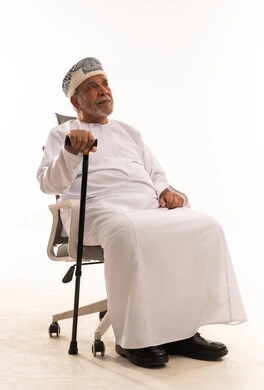 رجل عماني مسن بالزي التقليدي مع عصا مشي