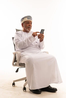 رجل عماني مسن يستخدم الهاتف الذكي بخلفية بيضاء
