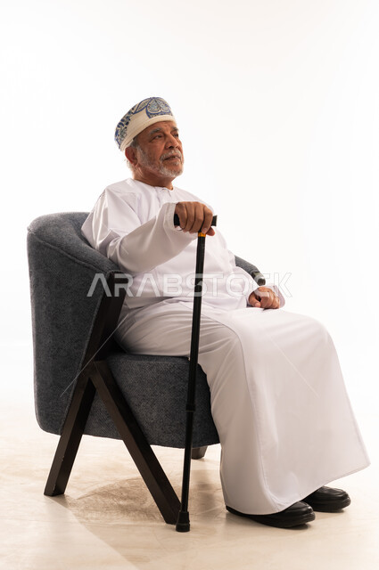 رجل عماني مسن يرتدي الزي التقليدي مع عصا