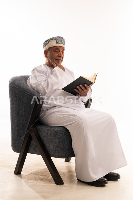 Elderly Omani Man Reading Book in Traditional Dress