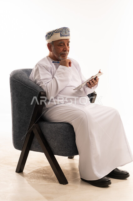 Elderly Omani Man Reading Tablet in Traditional Dress