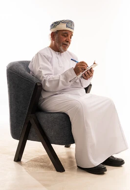 رجل عماني مسن يكتب على لوحة ملاحظات