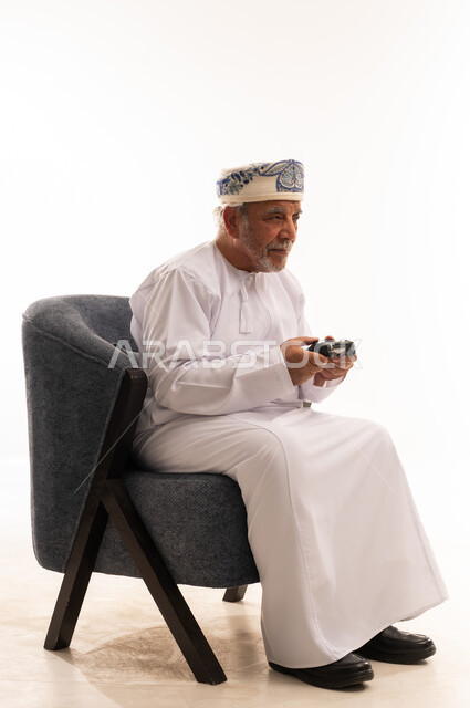 رجل عماني مسن يلعب ألعاب الفيديو في الاستوديو