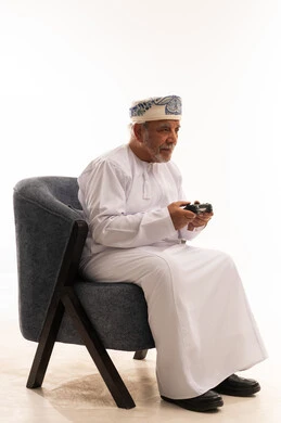 رجل عماني مسن يلعب ألعاب الفيديو في الاستوديو