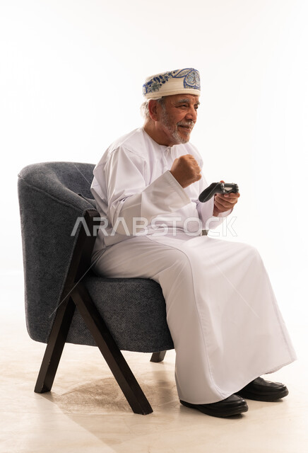 رجل عماني مسن يلعب ألعاب الفيديو في الاستوديو