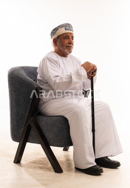 رجل عماني مسن بالزي التقليدي وعصا المشي