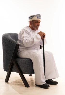 رجل عماني مسن بالزي التقليدي يمسك عصا