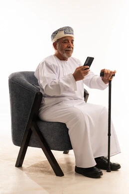 رجل عماني مسن يستخدم هاتف ذكي بخلفية بيضاء