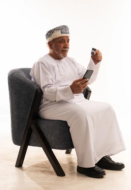 رجل عماني مسن يستخدم الهاتف وبطاقة الائتمان