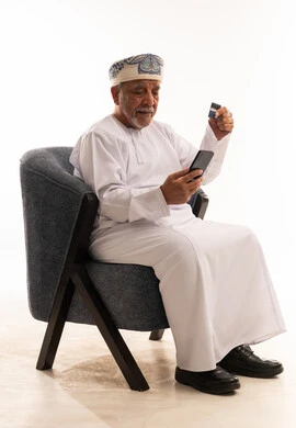 Omani Senior Man Using Credit Card and Smartphone