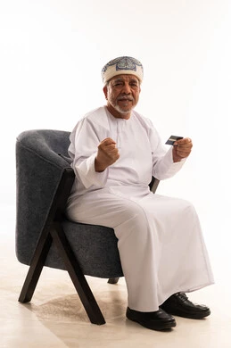 رجل عماني كبير في السن يحمل بطاقة ائتمان بنجاح