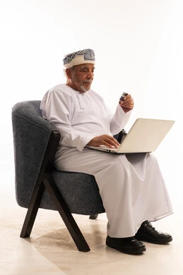 Omani Senior Man Using Laptop and Credit Card