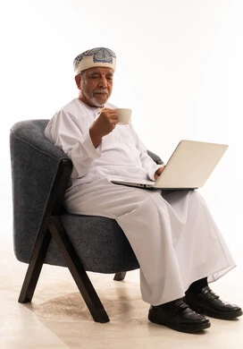 رجل عماني مسن يستخدم المحمول مع فنجان قهوة