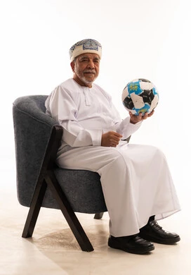 رجل عماني مسن بالزي التقليدي يمسك كرة قدم