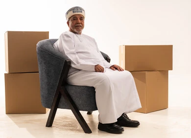 رجل عماني يجلس مع صناديق شحن كرتونية