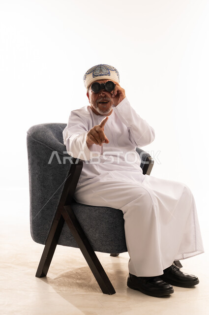 رجل عماني مسن يستخدم المنظار بالزي التقليدي