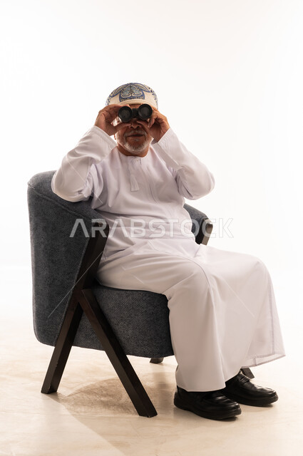 رجل عماني بالدشداشة البيضاء يستخدم منظار