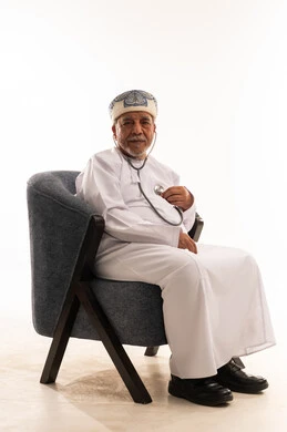 طبيب عماني مسن يحمل سماعة طبية بخلفية بيضاء