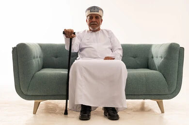 رجل عماني مسن يجلس على أريكة مع عصا