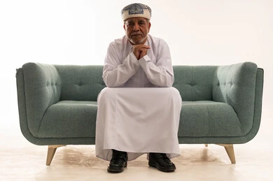 رجل عُماني مسن بالزي التقليدي على أريكة حديثة
