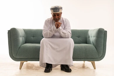 Elderly Omani Man Thinking on Sofa White Background