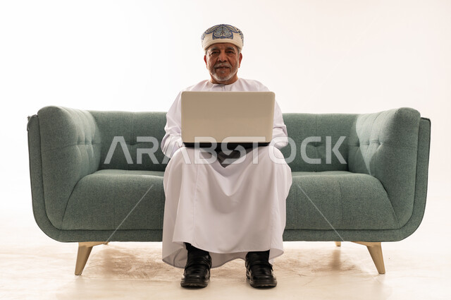Omani Senior Man Using Laptop on Sofa