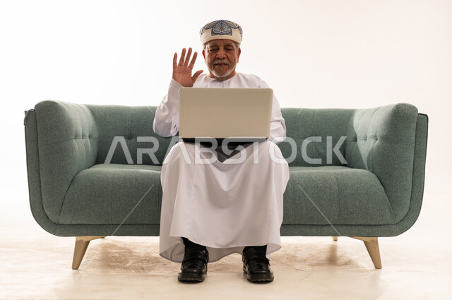 رجل عماني مسن يستخدم المحمول على الأريكة
