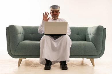 رجل عماني مسن يستخدم المحمول على الأريكة